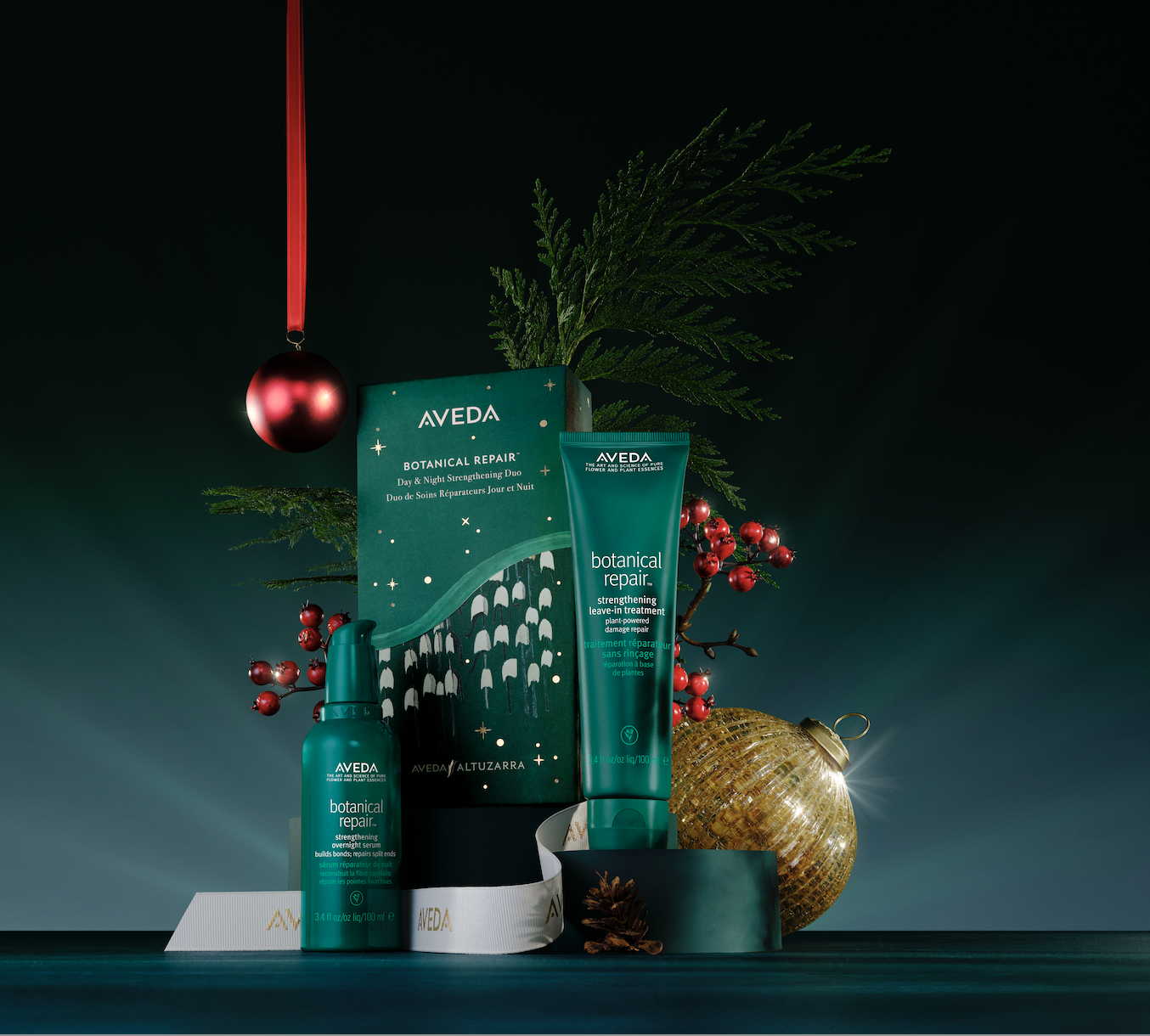 Aveda Botanical Repair products with holiday-themed packaging, placed among festive ornaments and greenery.